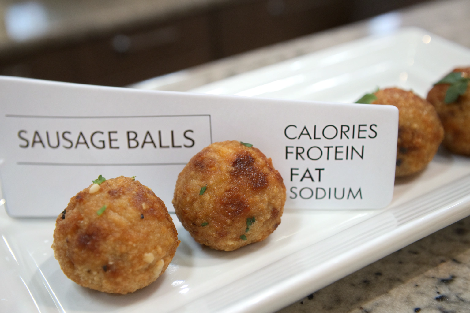 Four sausage balls on a white plate showing calorie content